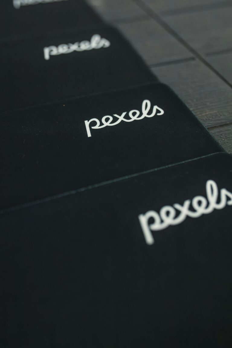 A close-up view of the Pexels logo displayed on a dark surface in a repeating pattern.